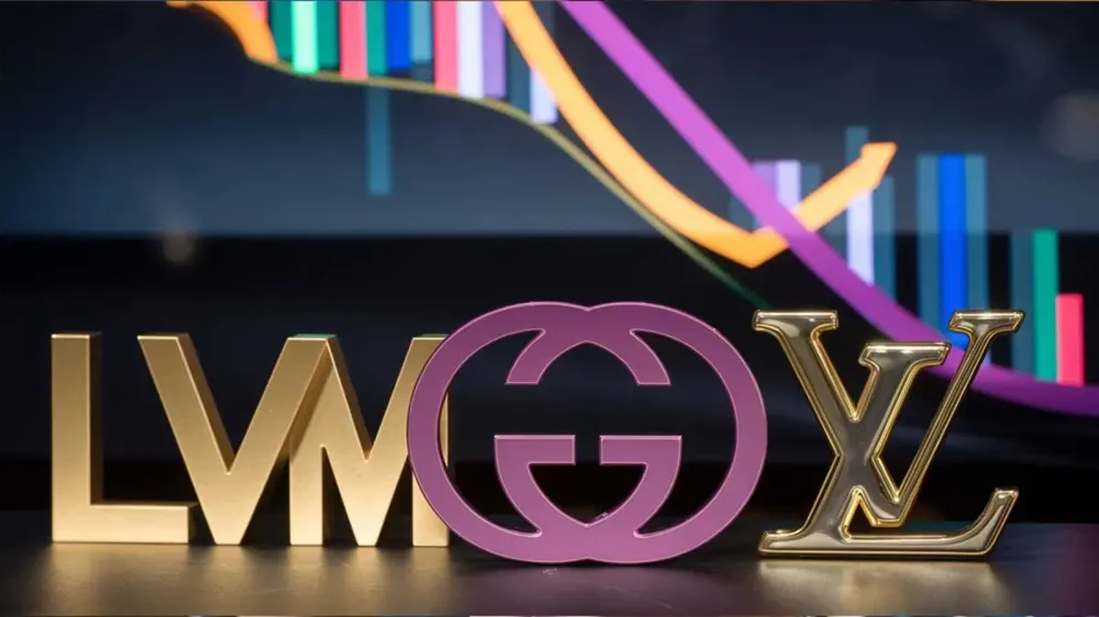 Logos de LVMH, Gucci et Louis Vuitton devant un graphique boursier en baisse, symbolisant les difficultés financières du secteur du luxe.