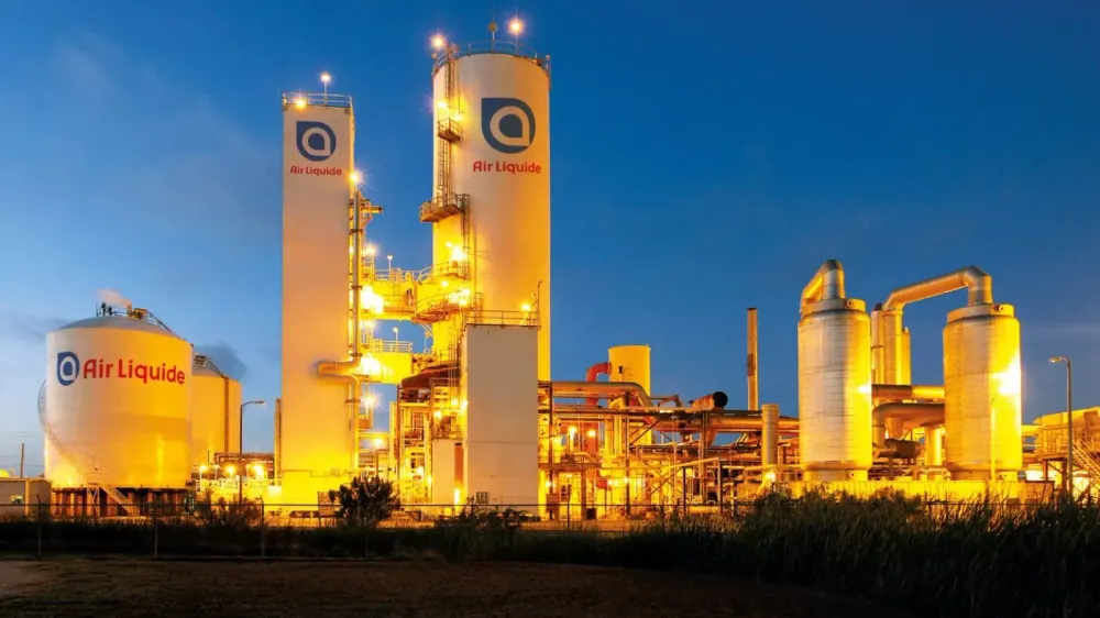 Usine Air Liquide illuminée la nuit, montrant des réservoirs et des structures industrielles avec le logo Air Liquide.