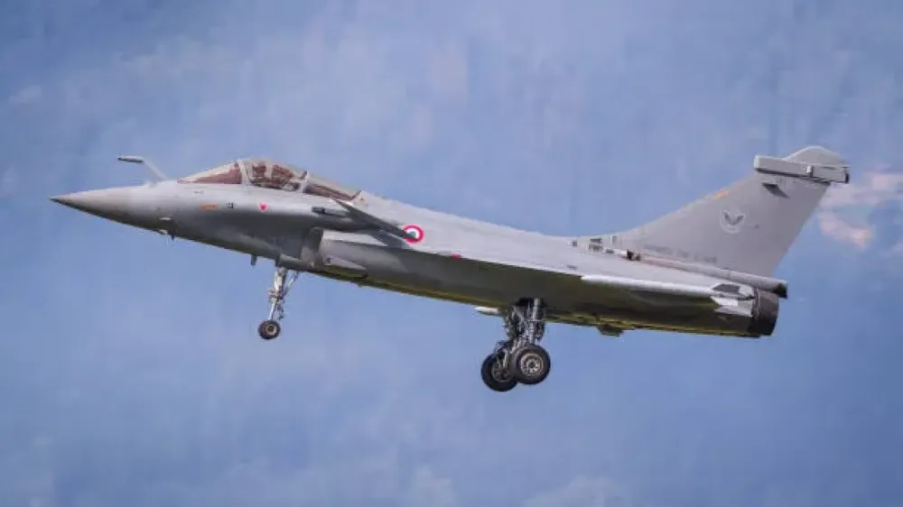Avion de chasse Rafale de Dassault Aviation en vol, train d'atterrissage sorti, sur fond de ciel bleu nuageux.