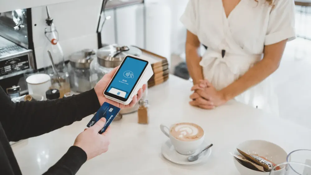 Paiement sans contact avec une carte Visa dans un café, illustrant l'utilisation quotidienne de la carte et la technologie de paiement moderne.