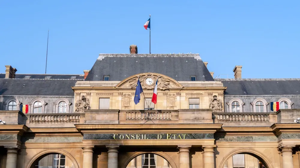 Façade du Conseil d'État à Paris, avec les drapeaux français et européen, symbole de l'administration et des politiques publiques.