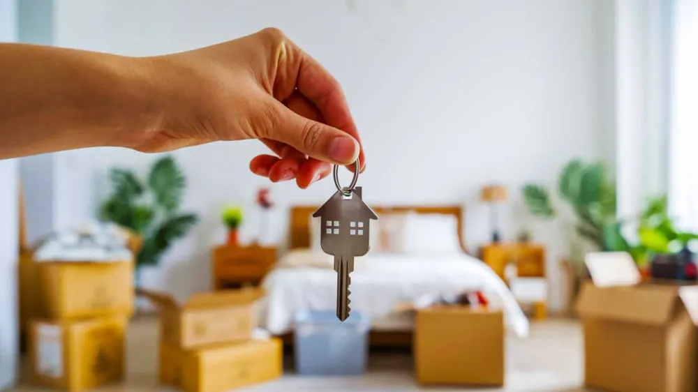 Une main tenant une clé en forme de maison, symbolisant l'acquisition d'un logement pour un investissement locatif étudiant.