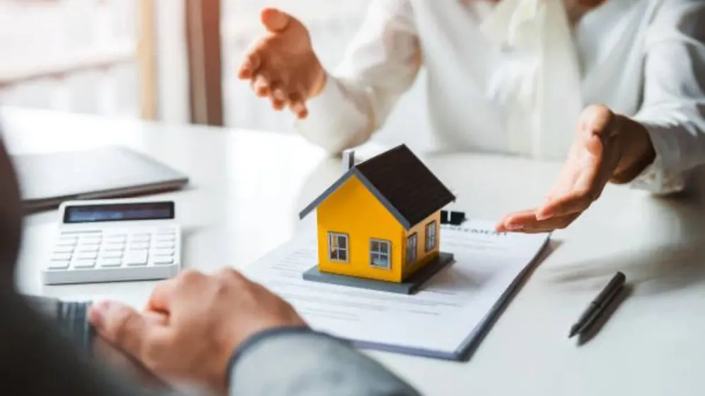 Une maquette de maison sur un contrat, symbolisant un prêt immobilier.