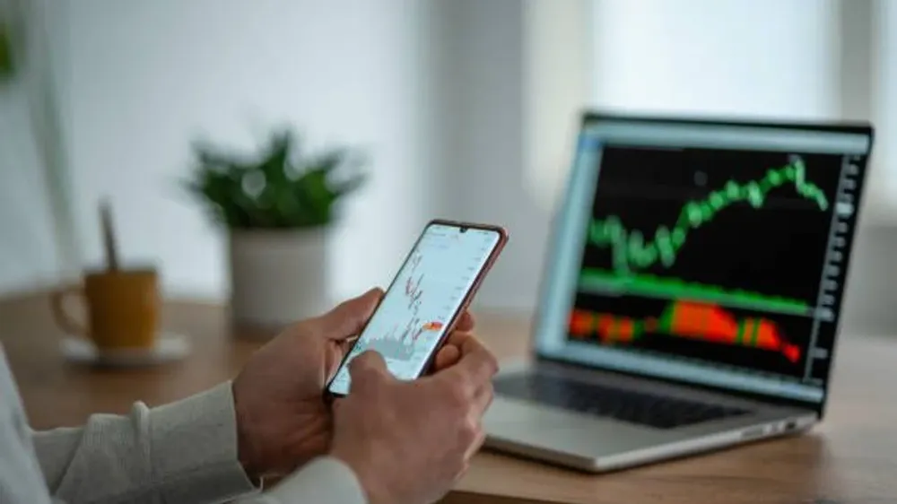 Un trader débutant analyse les graphiques boursiers sur son téléphone et son ordinateur portable.