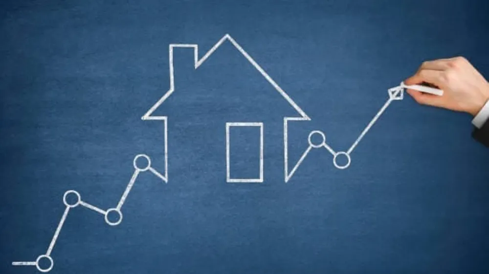 Graphique de l'augmentation des prix de l'immobilier dessiné à la craie sur un tableau bleu, avec une maison au centre.