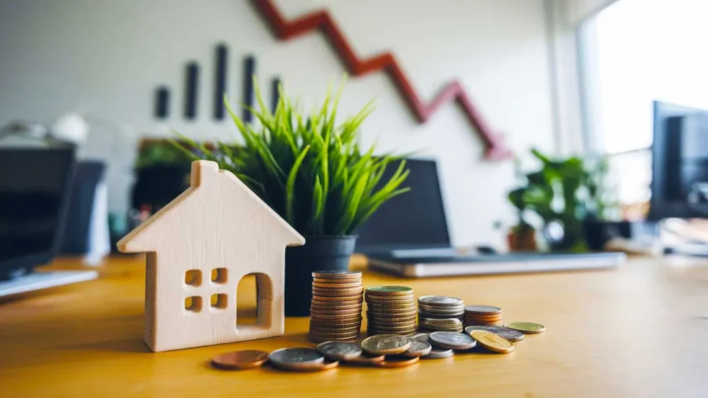 Baisse des prix de l'immobilier : une maison en bois et des pièces symbolisent la crise du marché immobilier français.