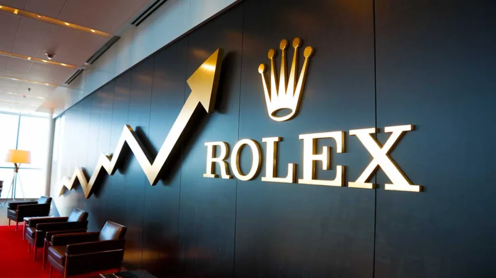 Logo Rolex doré sur un mur sombre, accompagné d'un graphique boursier ascendant, symbolisant la croissance et le succès de la marque.