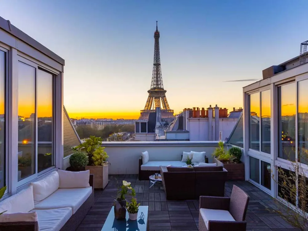 Terrasse luxueuse avec vue imprenable sur la Tour Eiffel au coucher du soleil, symbole de l'immobilier d'exception à Paris.