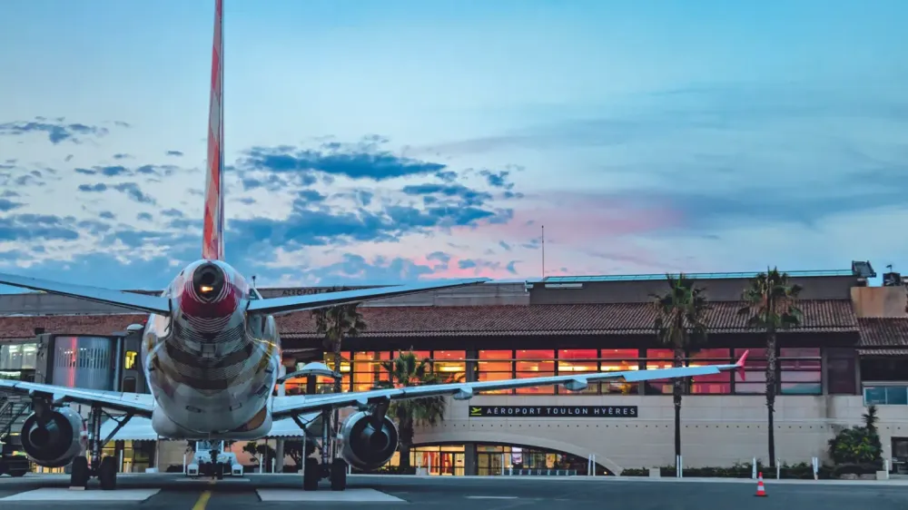 Avion à l'aéroport de Toulon Hyères, ciel nuageux au coucher du soleil, bâtiment de l'aéroport en arrière-plan.