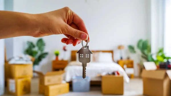 Une main tenant une clé en forme de maison, symbolisant l'acquisition d'un logement pour un investissement locatif étudiant.