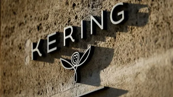 Logo de Kering sur un mur texturé, avec le nom de l'entreprise et un symbole distinctif.
