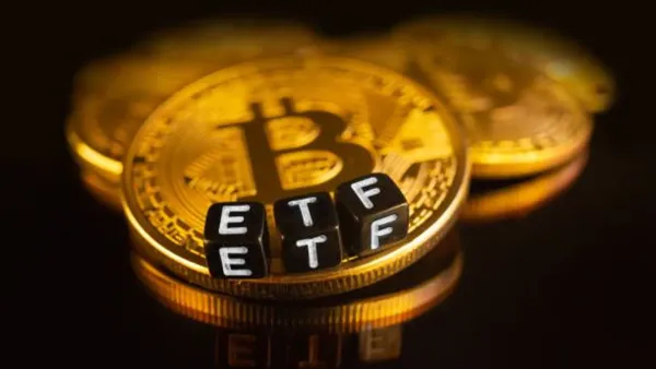 Pièces Bitcoin avec des dés noirs épelant ETF, représentant un ETF Bitcoin.