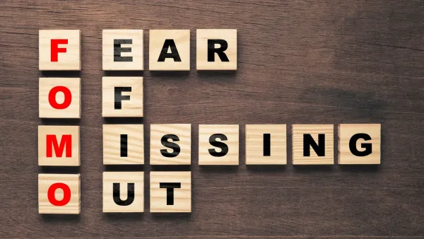 Le mot FOMO (Fear Of Missing Out) écrit avec des cubes en bois sur une table en bois.