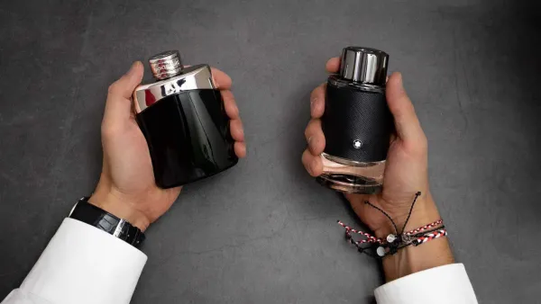 Deux flacons de parfum Montblanc Legend, un noir brillant et un noir texturé, tenus par des mains avec une montre et des bracelets.