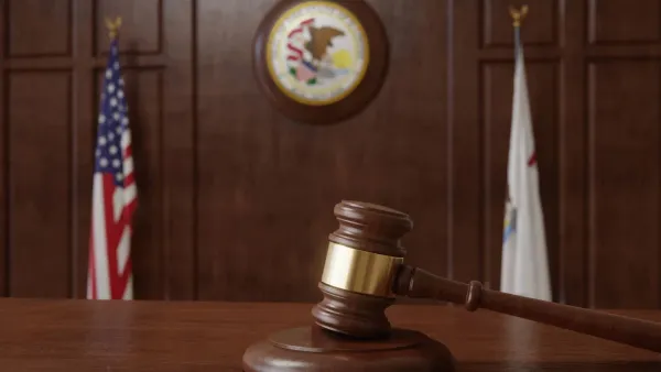 Un marteau de justice sur un bureau en bois, avec des drapeaux américain et d'état en arrière-plan.