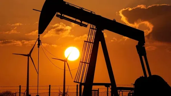 Silhouette d'un puits de pétrole et d'éoliennes au coucher du soleil, symbolisant le contraste entre les énergies fossiles et renouvelables.