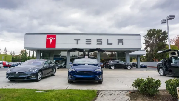 Un concessionnaire Tesla avec plusieurs voitures exposées devant, dont une avec les portes papillon ouvertes.