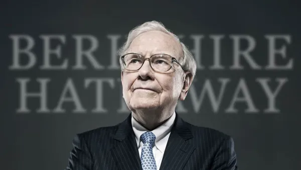 Warren Buffett, PDG de Berkshire Hathaway, portant des lunettes et un costume rayé, avec le nom de sa société en arrière-plan.
