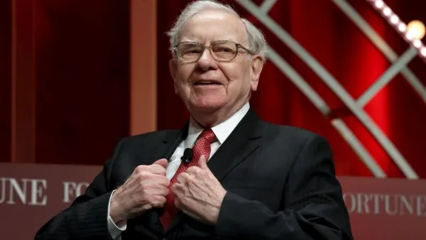 Warren Buffett souriant en costume et cravate rouge.